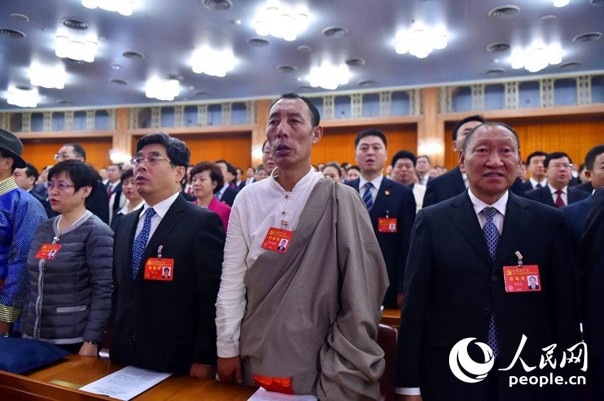 中國共產黨第十九次全國代表大會開幕會現場，代表起立唱國歌。（人民網記者 翁奇羽 攝）