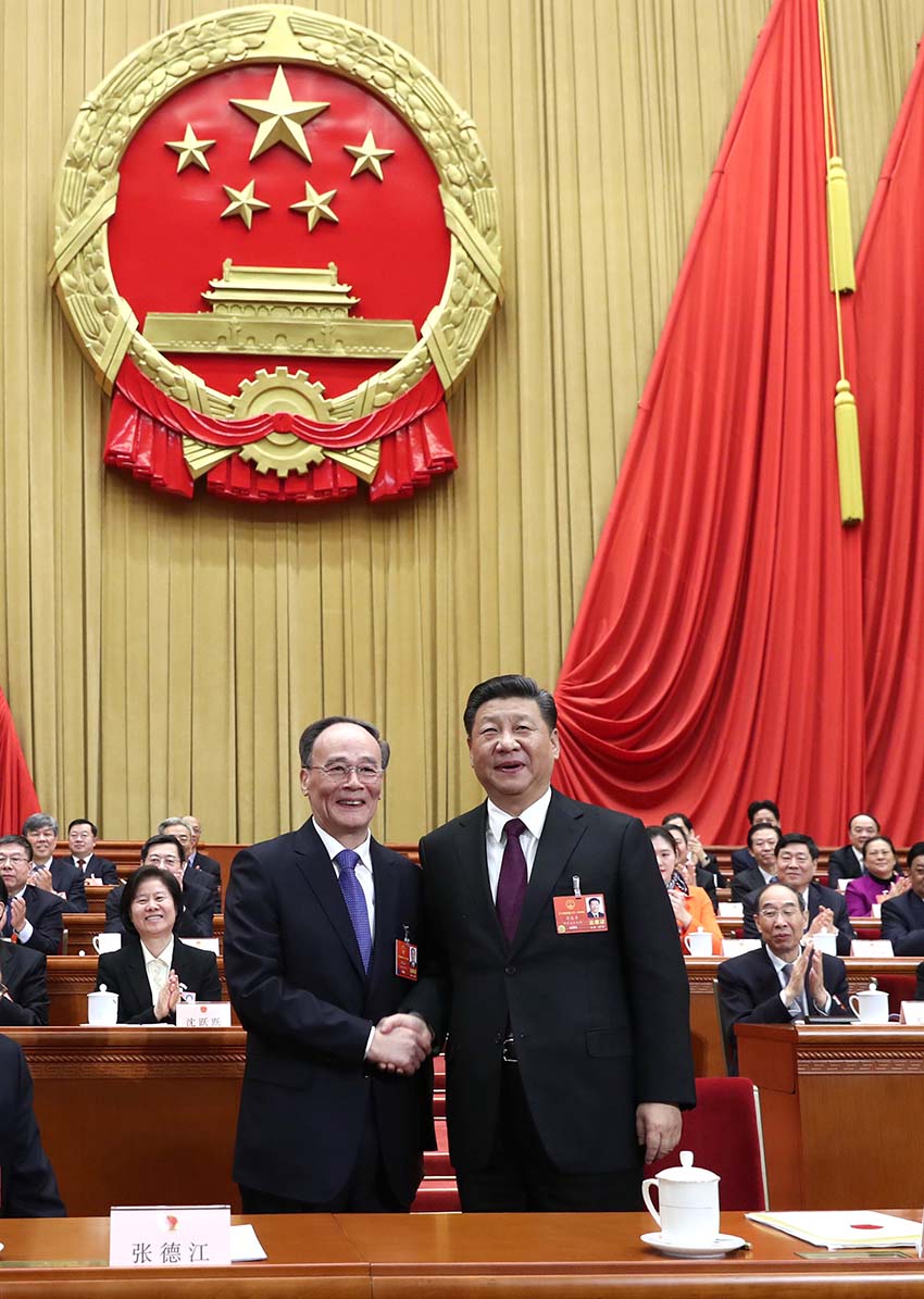 3月17日，十三屆全國人大一次會議在北京人民大會堂舉行第五次全體會議。習近平當選中華人民共和國主席、中華人民共和國中央軍事委員會主席。這是習近平在主席台上同新當選的國家副主席王岐山握手。新華社記者 鞠鵬 攝