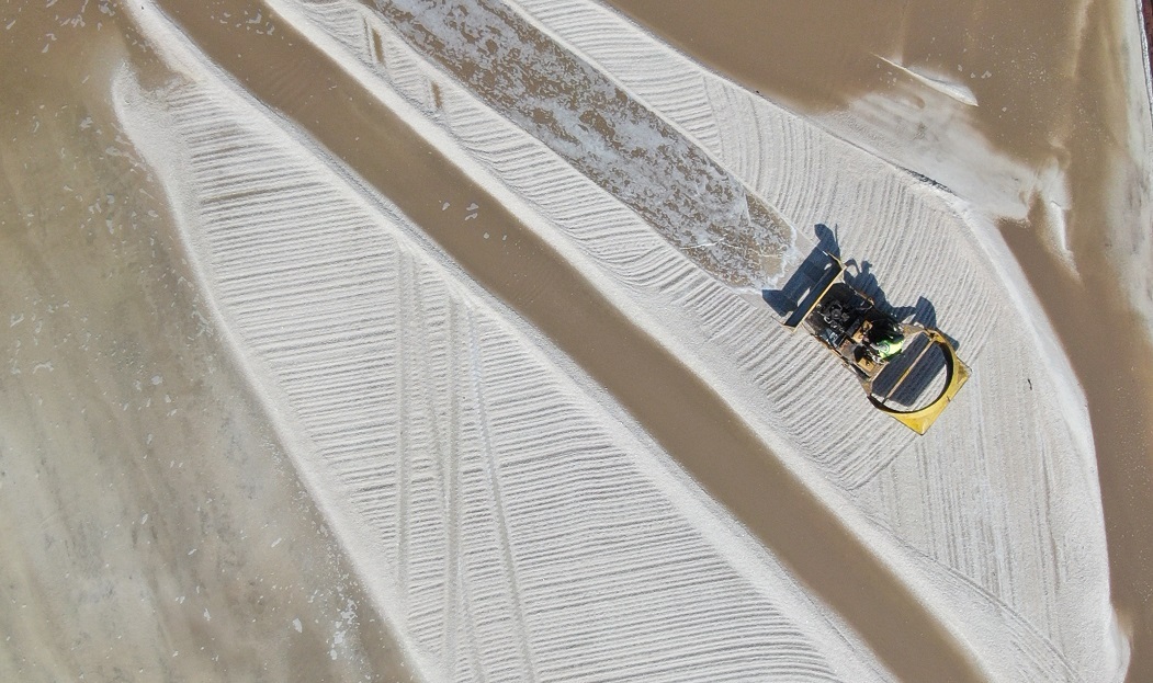 工人在山東省濱州市沾化區濱海鎮金盛海洋鹽場收獲春鹽。