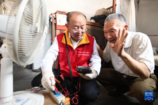 錢海軍（左）來到結對老人家裡，義務為老人維修家裡的老舊電器（2020年8月19日攝）。新華社發 姚科斌 攝