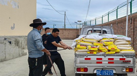 2022年8月17日，鄧官杰（左三）為同德縣唐谷鎮受災群眾搬運應急物資。（同德縣應急管理局供圖）