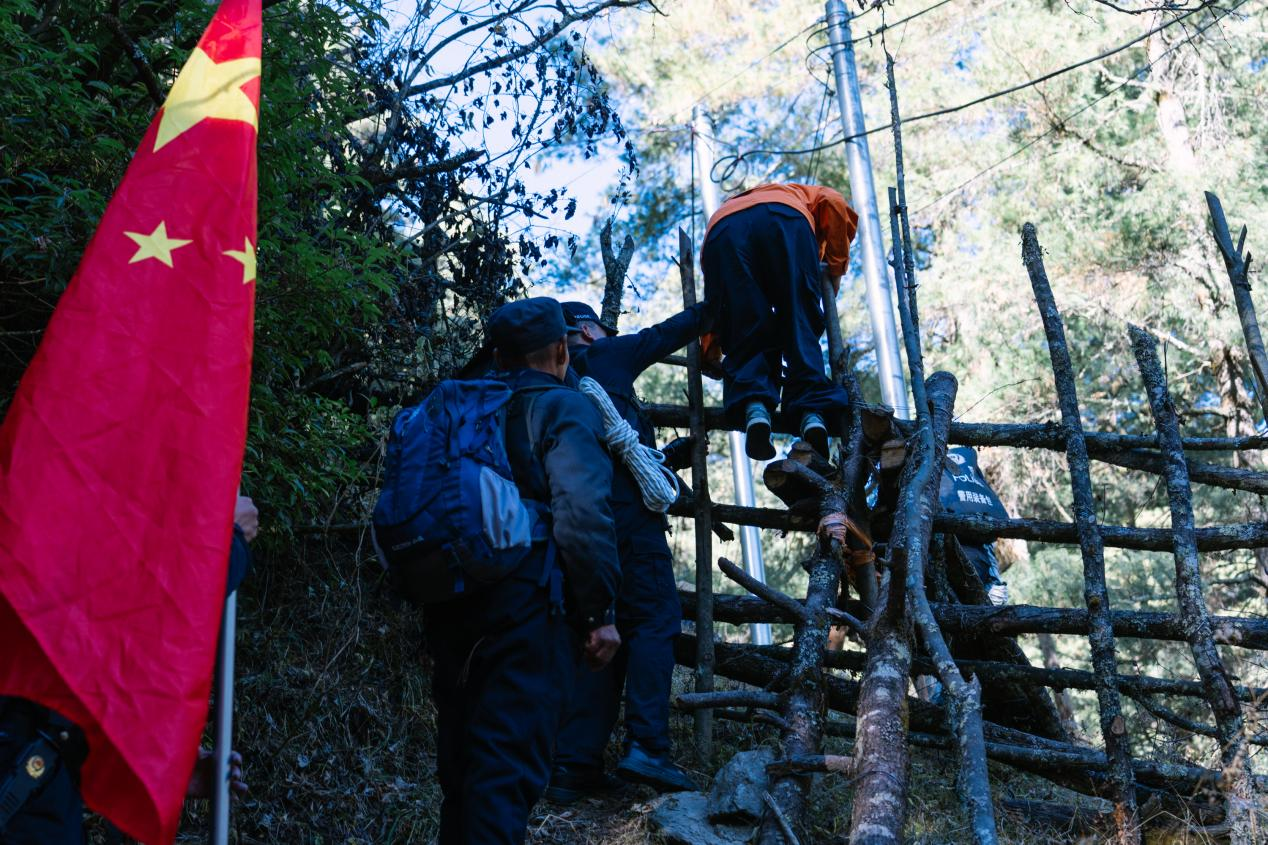 山路陡峭难行,民警互相搭手前进。人民网 石曲次旺摄