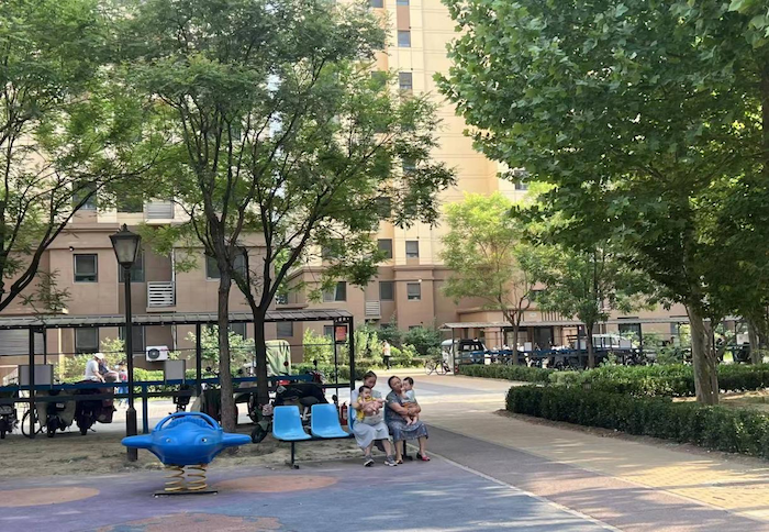 良乡镇回迁安置小区，居民坐在树下乘凉。人民网 高清扬摄